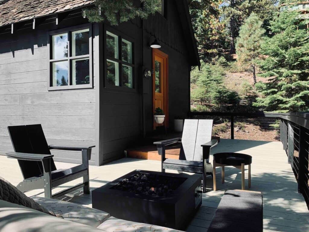 A small black cabin with an outdoor firepit and black seats outside on the deck, a popular Airbnb in Tahoe for couples and small groups.