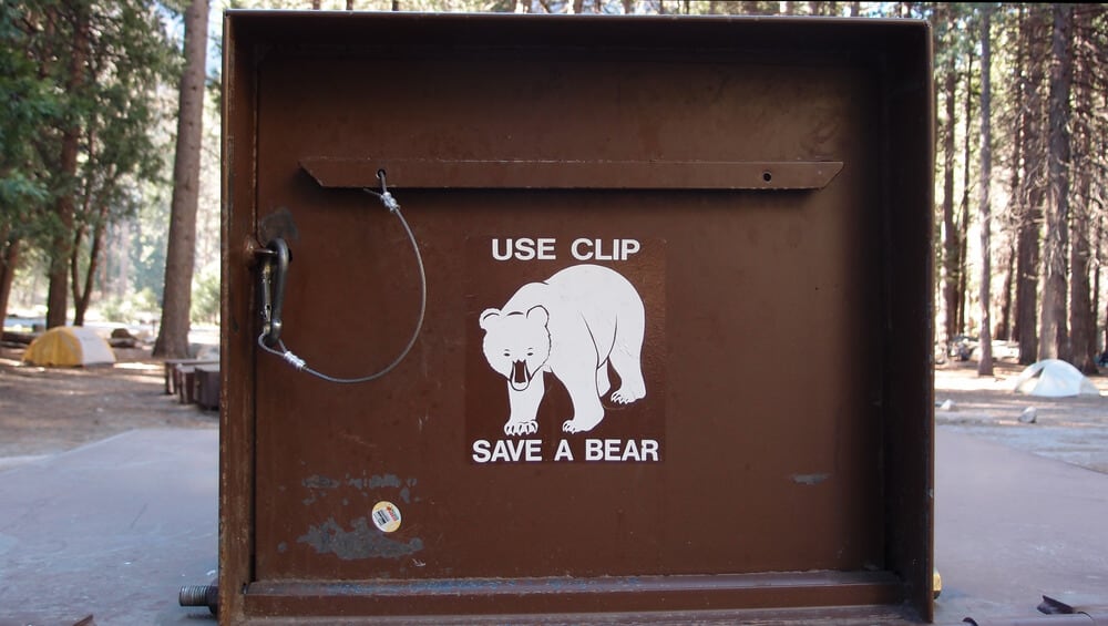 Brown bear proof dumpster that says "use clip, save a bear"