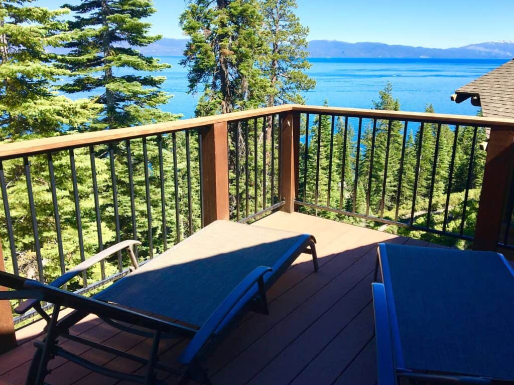 A lakefront cabin in Tahoe with a view, deck looking out with two chairs onto a brilliant turquoise water of the Lake.