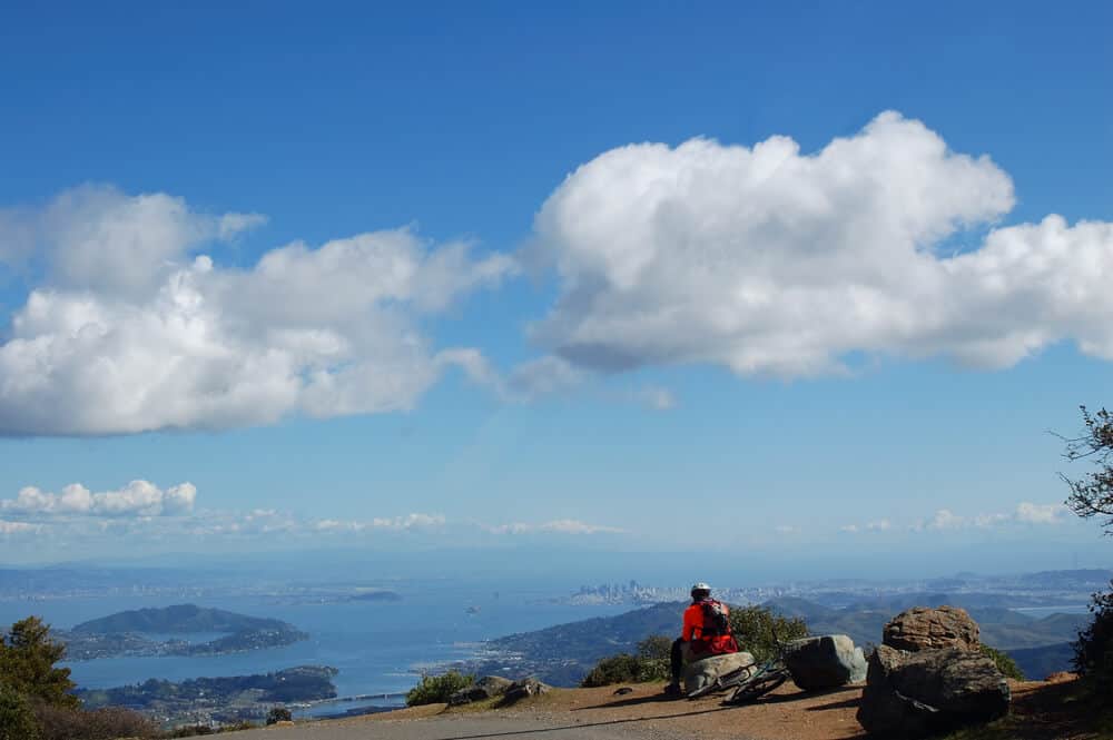Man in red jacket stopping to look at view over the Bay Area from Mt Tamalpais east summit.