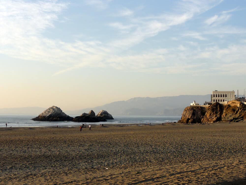 the sunset at ocean beach in california with sandy shore and building in the distance