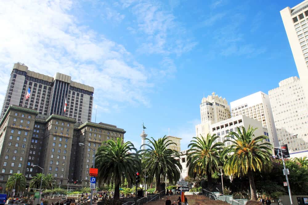 Palm trees in a share with lots of people in it surrounded by tall skyscrapers in Union Square San Francisco