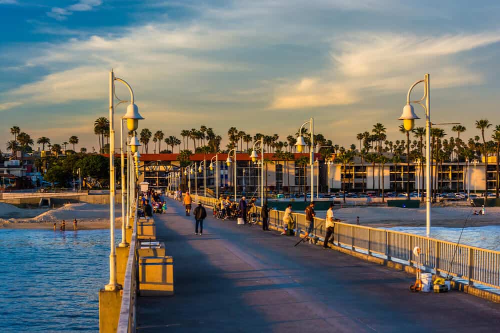 people on belmont pier in long beach at sunset with fishing rods and walking