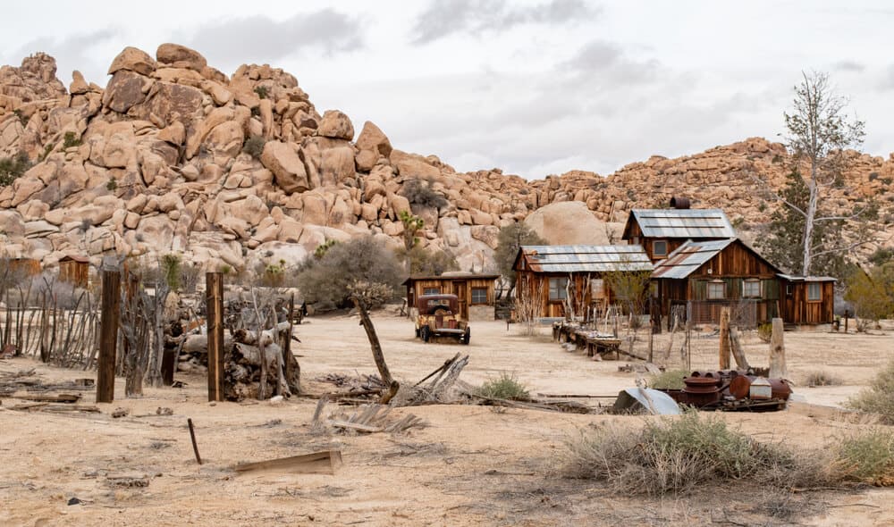 A dilapidated wood and tin roof mining house in the middle of the Joshua Tree landscape, a popular hiking destination also good for history lovers