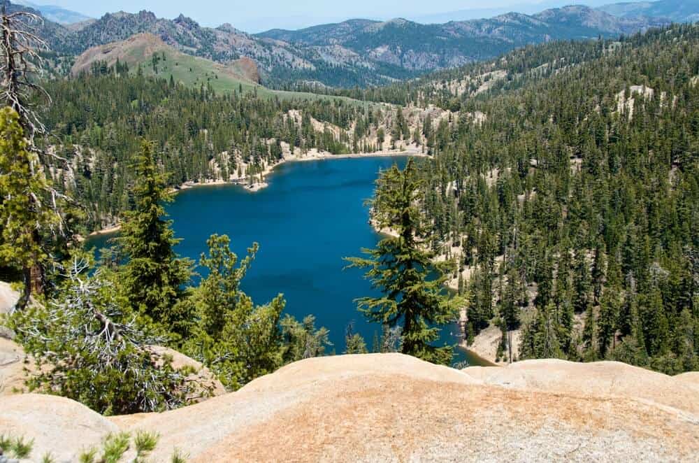 The waters of a lake below visible from Ebbets Pass, surrounded by trees and pines.