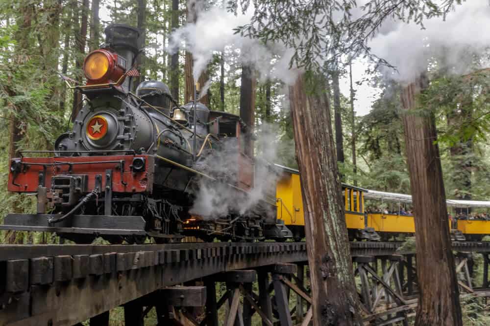 A steam train on a wooden track going through the redwods near Santa Cruz