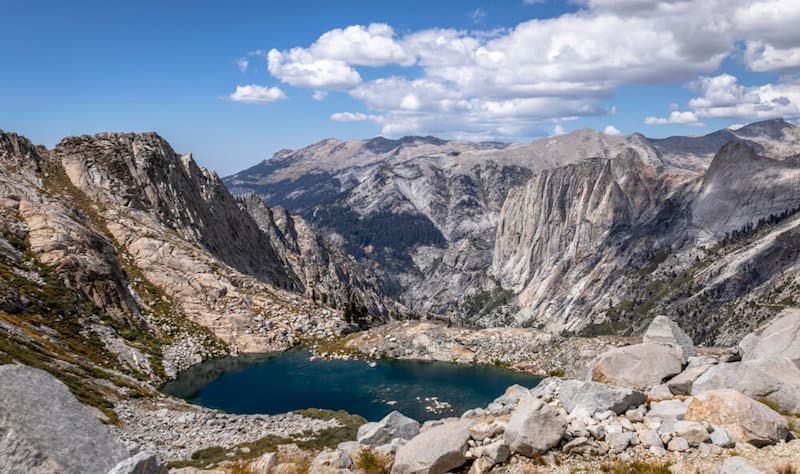 a still blue lake at the middle of a glacier basin between high sierra peaks