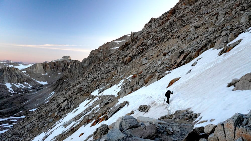 hiker on snow on a mountain face climbing a high sierra pass