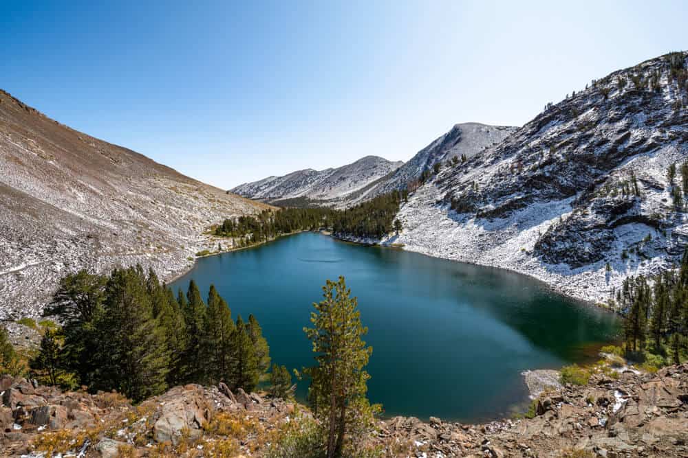 Brilliant turquoise lake in the middle of the alpine landscape of the High Sierras with a clear blue sky in the afternoon light
