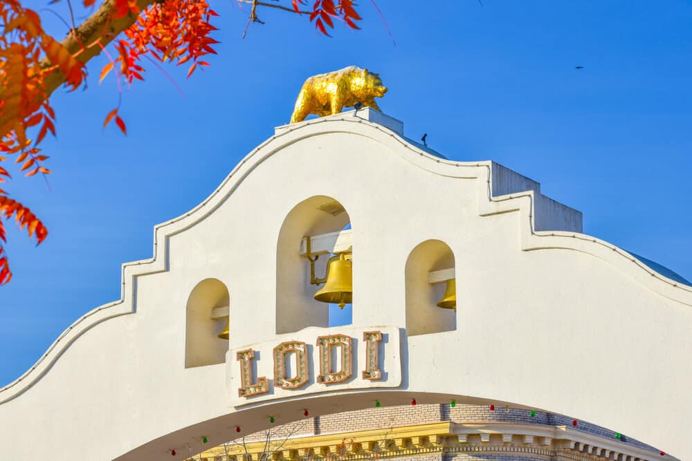 White arch that reads "LODI" with a gold bell and a golden bear atop, a California state symbol