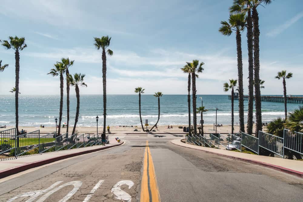 Street leading to the ocean surrounded by palm trees on a sunny day scootering around Oceanside California