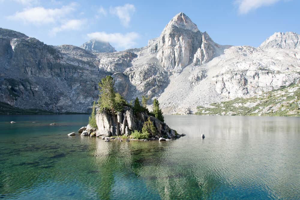 Small rocky islet in the middle of Rae Lake in the Sierra Nevadas, with turquoise water all around it.