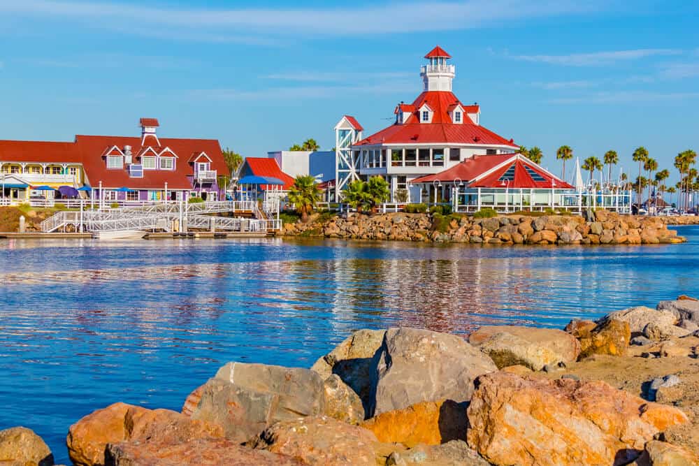 white building with red roof, palm trees and other colorful buildings on the marina