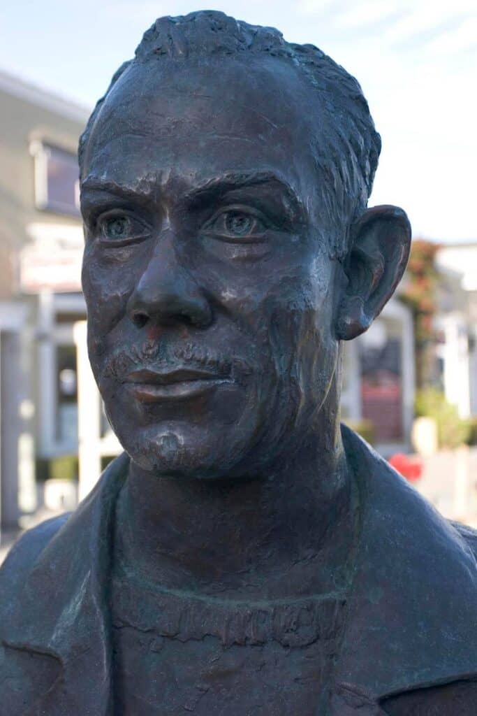 Statue showing John Steinbeck in Monterey with buildings behind it