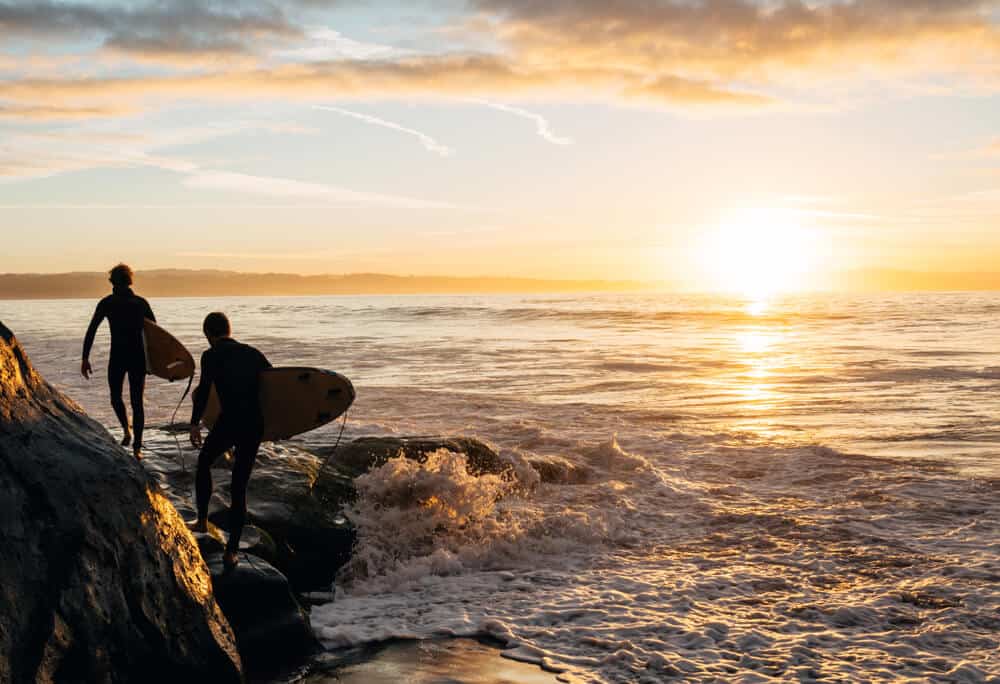 two surfers going to the water to surf