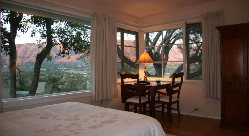 a room with a small table in the corner with a gorgeous view of the mountains at sunset