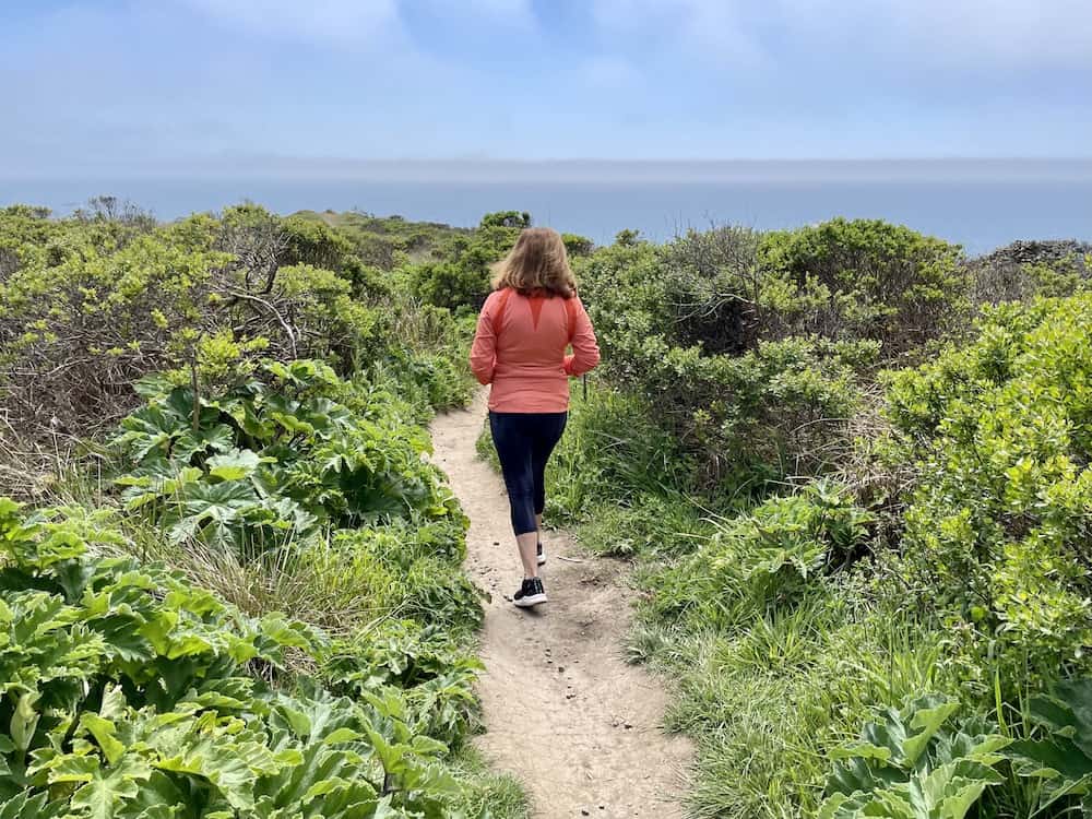 allison's mother wearing a orange jacket and leggings walking on the kortum trail in jenner