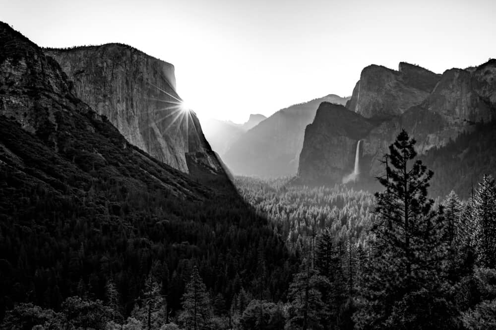 black and white view over tunnel view with a waterfall and sunbeam done in the ansel adams style