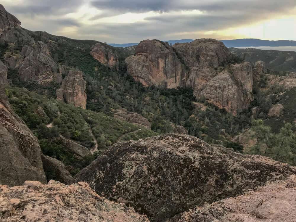 Sunset over Pinnacles National Park from an overlook with large red rocks and green trees