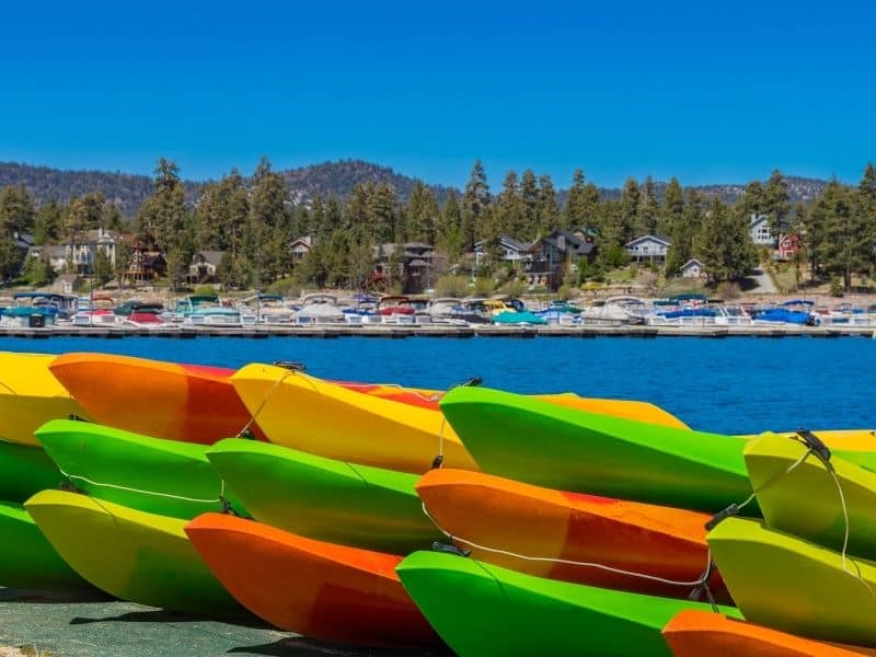 a pile of kayaks by the bank of lake big bear