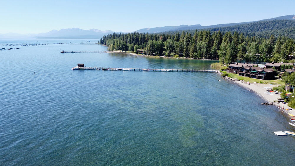 blueish green waters of commons beach, with lots of buildings on the shore of the lake and trees