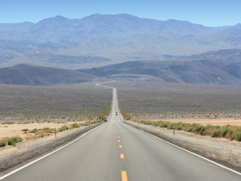 empty road in Death Valley california with beautiful badlands and mountains