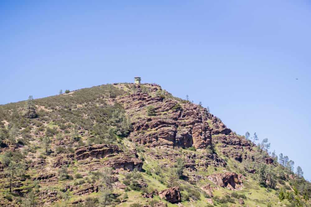 The fire tower atop North Chalone Peak in Pinnacles National Park, a mountain of reddish volcanic rock covered in desert-like greenery