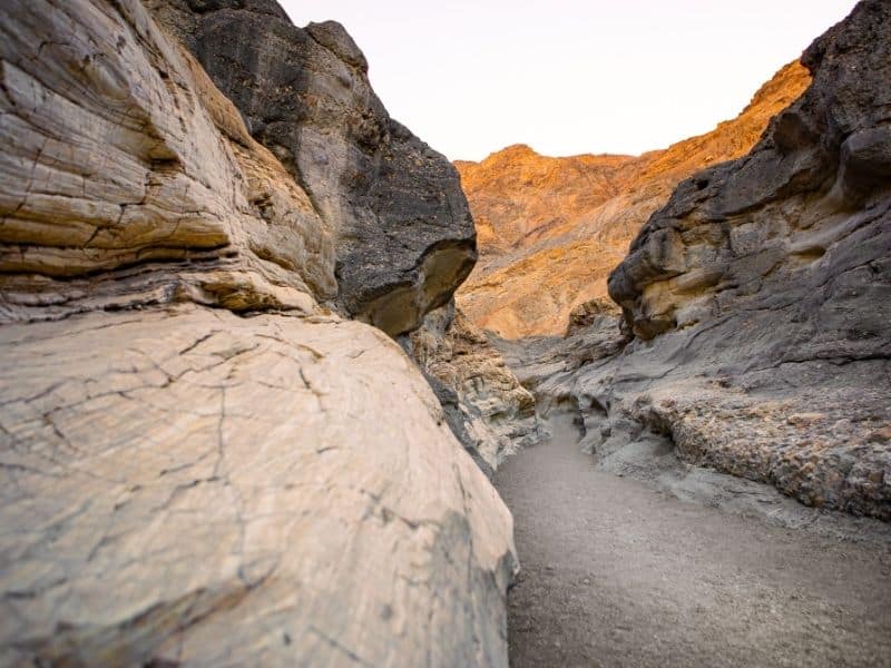 the slot canyons of mosaic canyon with sandy ground and orange and whiteish brown rock