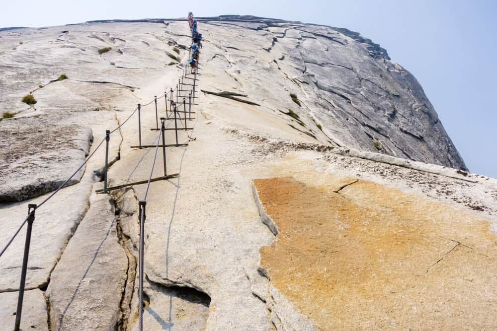 people climbing up the cables of half dome in yosemite, close up of the cables people use to climb to the top