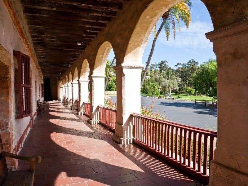 the archways and railings of the santa barbara mission with palm trees in front