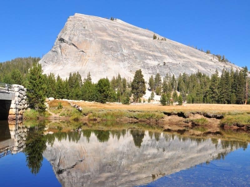 a large granite dome looming over a lake with a perfect mirrored reflection