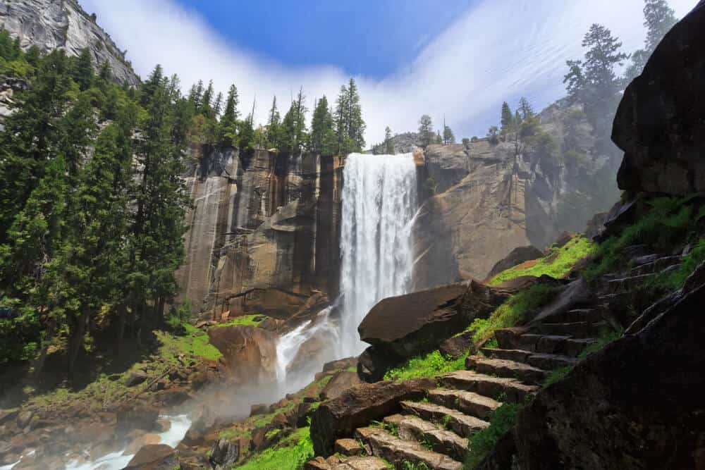 vernal fall single drop waterfall next to stone steps trail on a sunny day