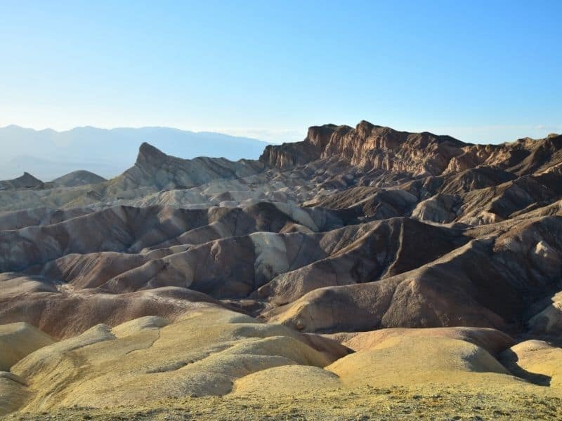 the colorful yellow brown and white rocks of zabriskie point in the later afternoon sun