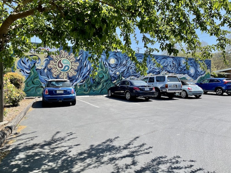 a parking lot with cars in it and a blue toned mural