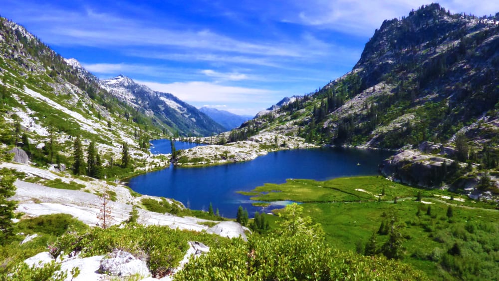 view of brilliant blue lakes surrounded by greenery and trees and mountains