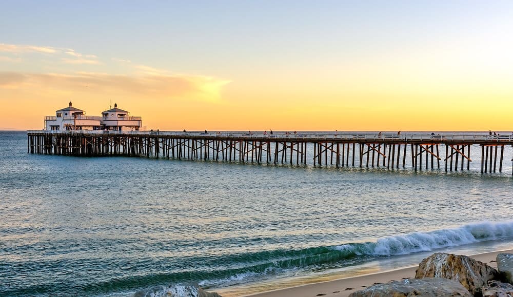 photo of the malibu pier at sunset with the pacific ocean illuminated by sunset colors