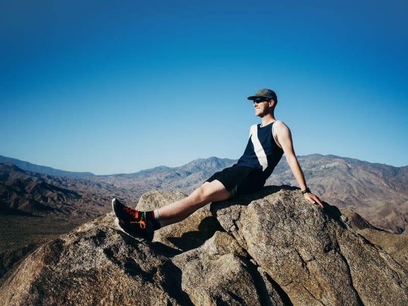 man sitting atop rocks at the summit of Murray peak aka murray hill