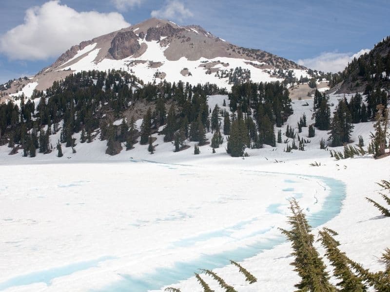 frozen lake at manzanita lake with a view of a snow covered mt lassen in the distance on a sunny day in winter