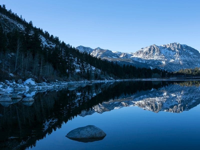 still unfrozen lake of june lake in winter, with snow on the rocks and on nearby mountains