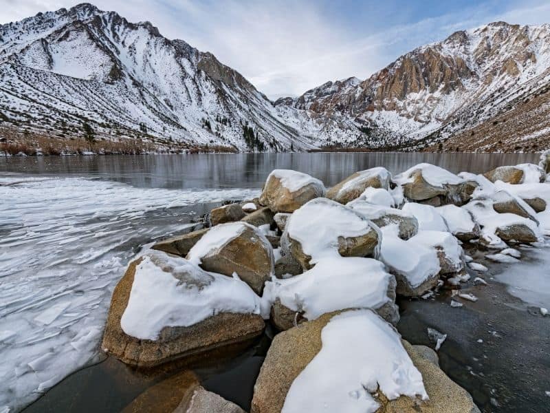 rocks covered in snow at the base of convict lake in the eastern sierras