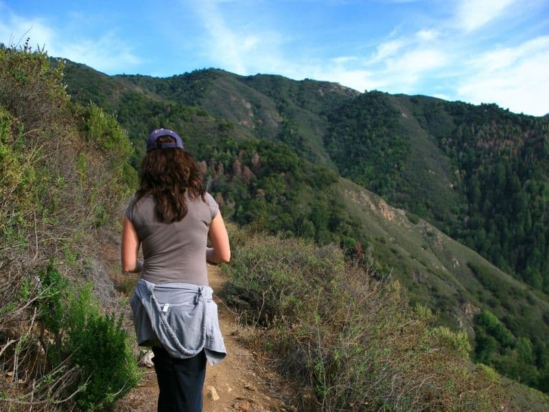 Hiker wearing a short sleeve shirt with a hoodie around her waist, showing how to wear layers in Big Sur