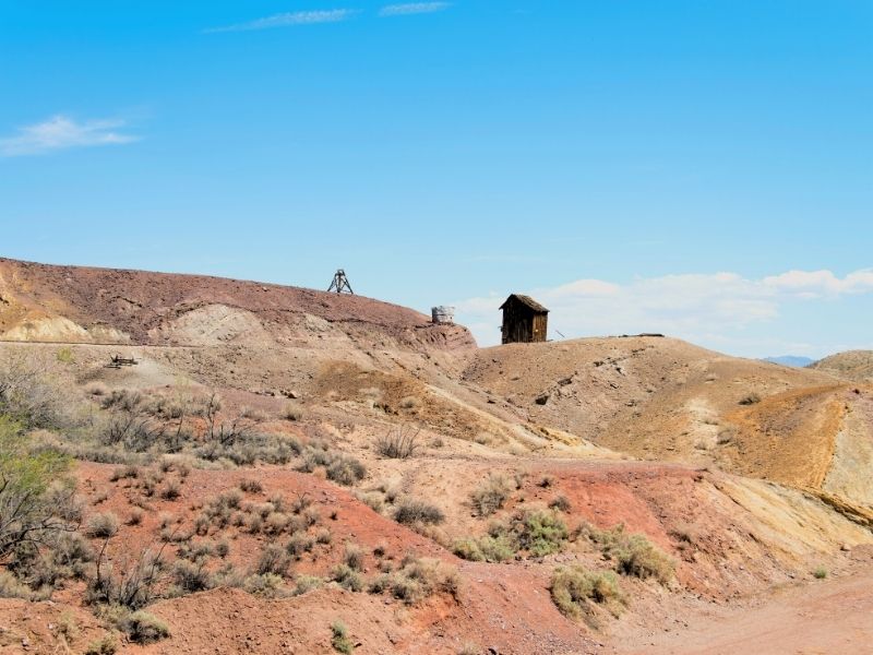 rugged red and orange hills with a small building on it in the california ghost town of calico