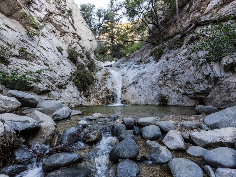 a beautiful but small waterfall in angeles national forest falling into a small pool strewn with rocks