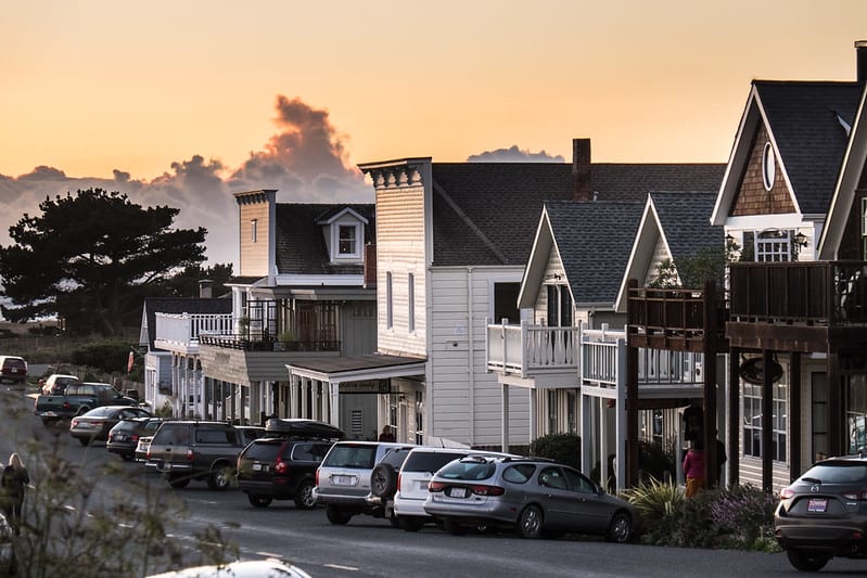 a row of buildings in mendocino downtown with sunset and fog coming in