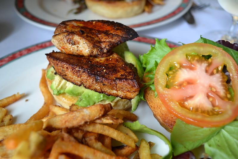 two slices of seared tuna on a bun with french fries at a local restaurant