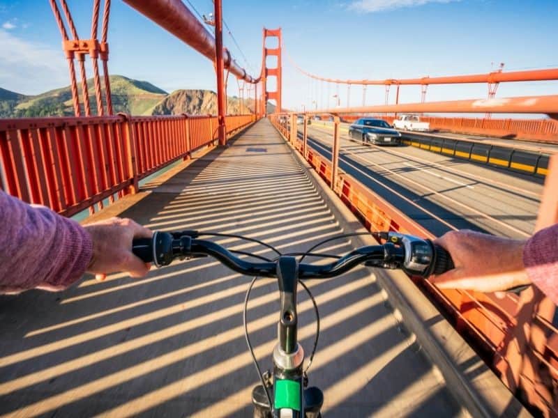 a person's hands on a set of bicycle handlebars on an empty walkway on the golden gate bridge