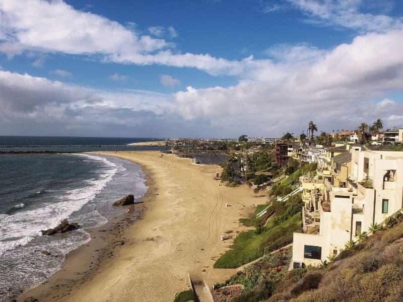 luxury beachfront houses in front of corona del mar state beach with cloudy sky