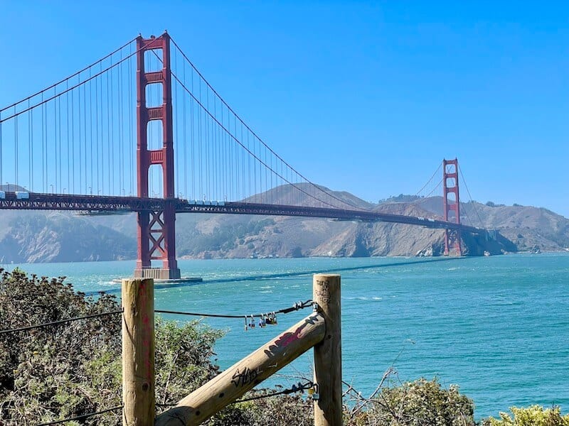 view of the water below the golden gate bridge and the red spans of the suspension bridge and hills behind it