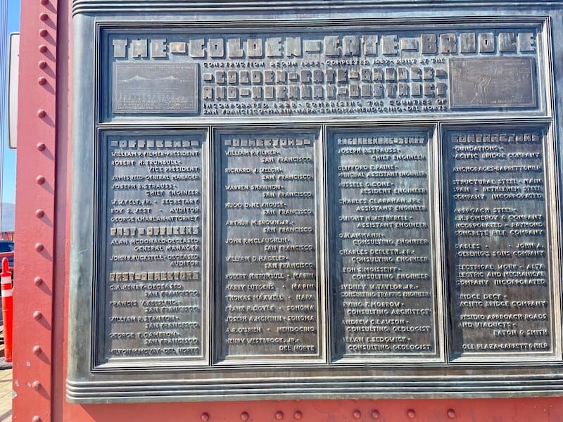 sign for the golden gate bridge with brass and colorful red bridge color