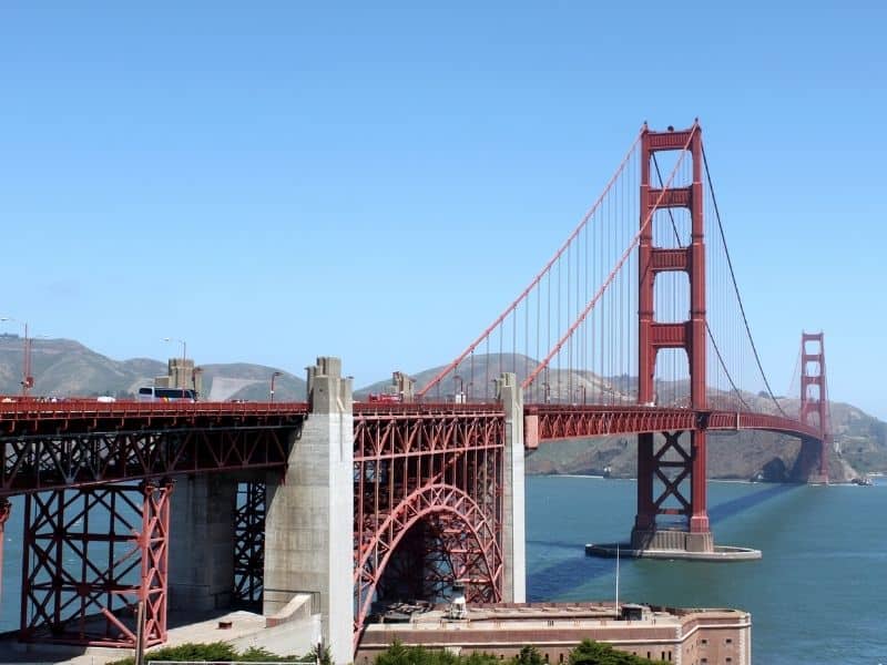 seeing the arch and the span of the golden gate bridge with its two red towers crossing over the blue waters of the bay